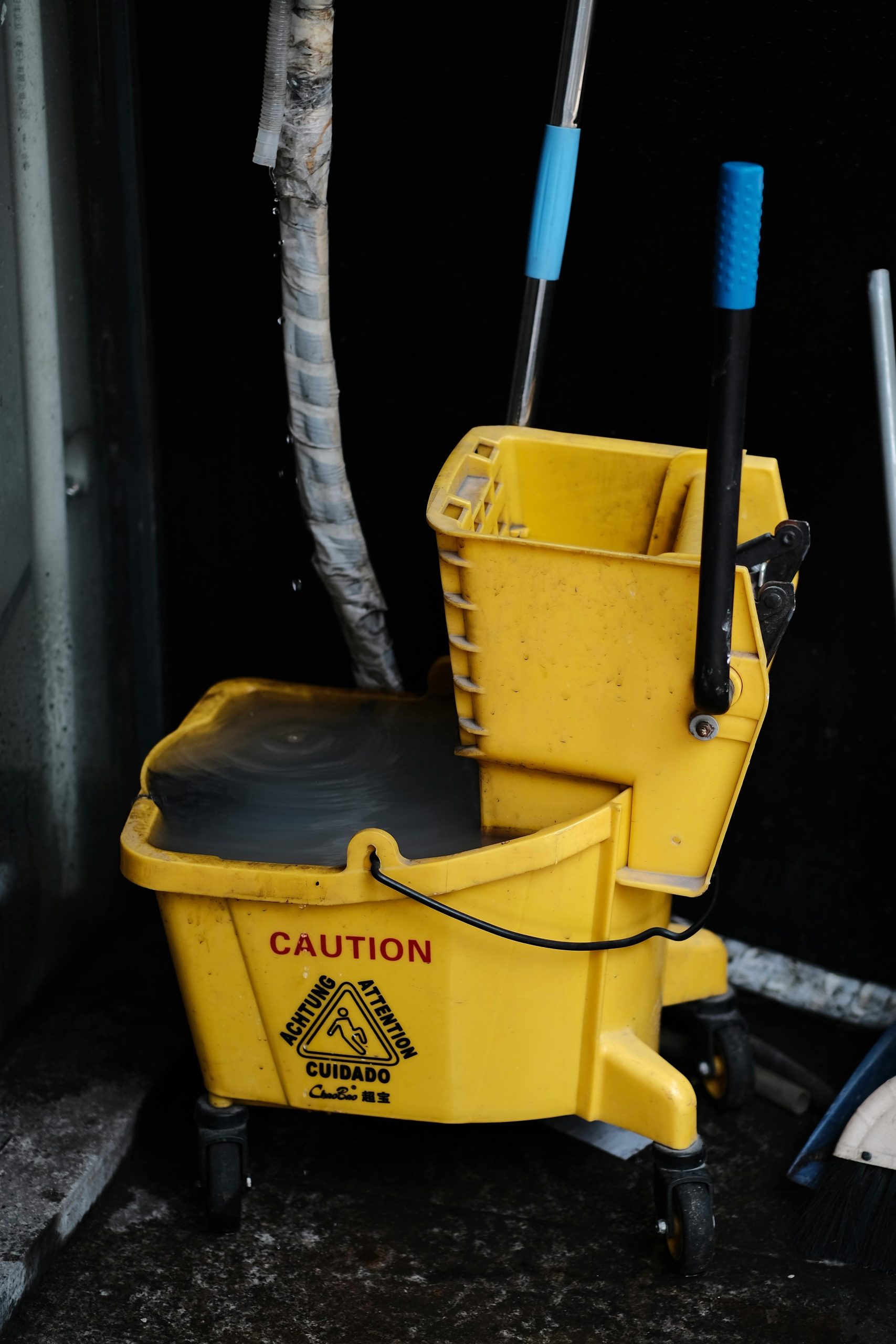 Commercial Floor & Carpet Care Close-up of a yellow mop bucket with caution sign, ideal for cleaning and maintenance themes.