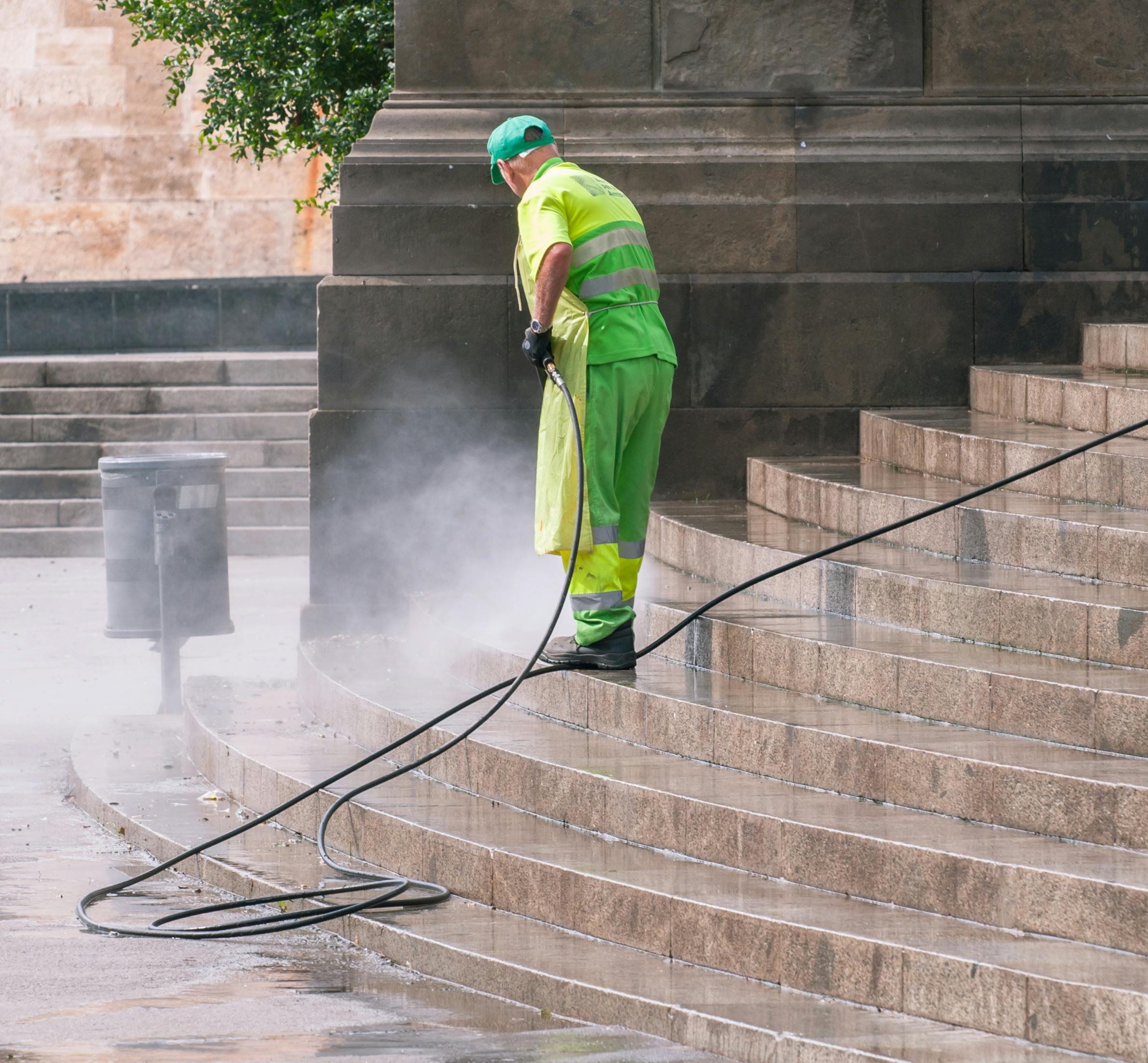 Pressure Washing A street worker pressure washes stone stairs in a public park, ensuring cleanliness and safety.